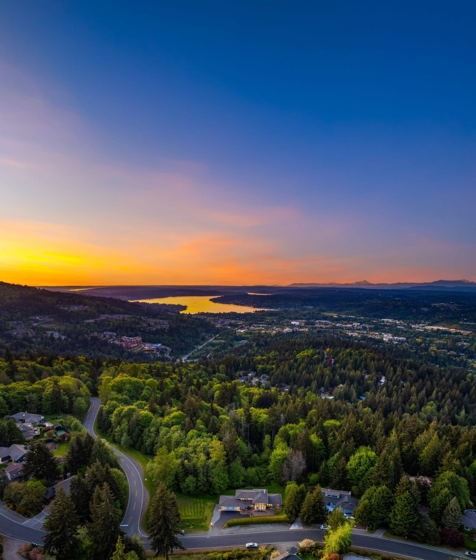 Stunning aerial view of a vibrant sunset over Lake Sammamish, showcasing lush greenery and residential areas in the Pacific Northwest.