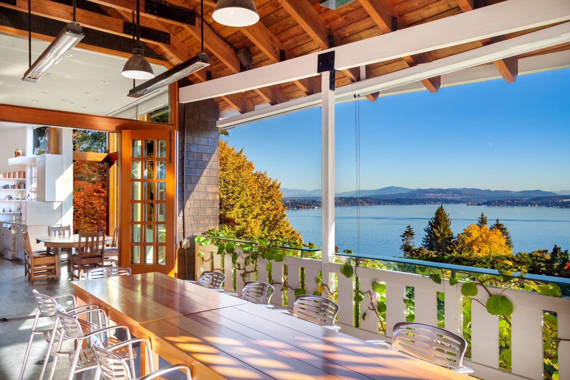 Bright and airy dining space with a large wooden table, featuring modern metal chairs and expansive windows showcasing stunning views of the water and mountains, located in the Pacific Northwest.