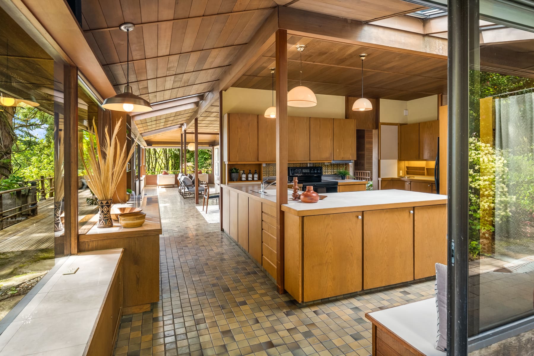 Spacious modern kitchen with wood cabinetry and large windows showcasing lush greenery, located in the Pacific Northwest.