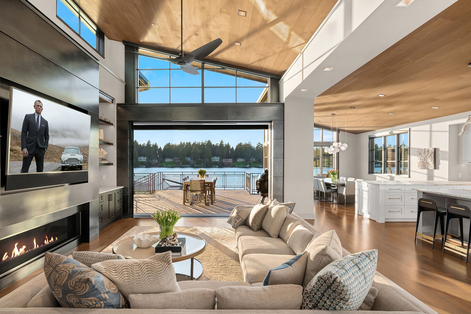 Modern waterfront living room with large windows showcasing serene views, featuring a cozy sectional sofa, sleek fireplace, and stylish decor in a Pacific Northwest home.