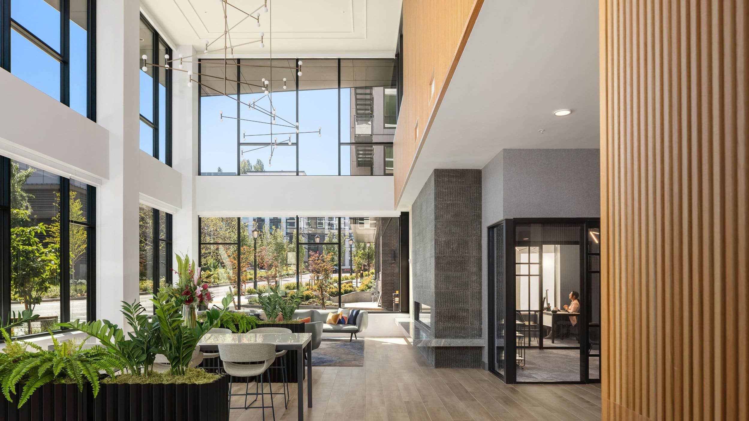 Modern living space featuring expansive windows, elegant lighting, and lush greenery, located in the Pacific Northwest.