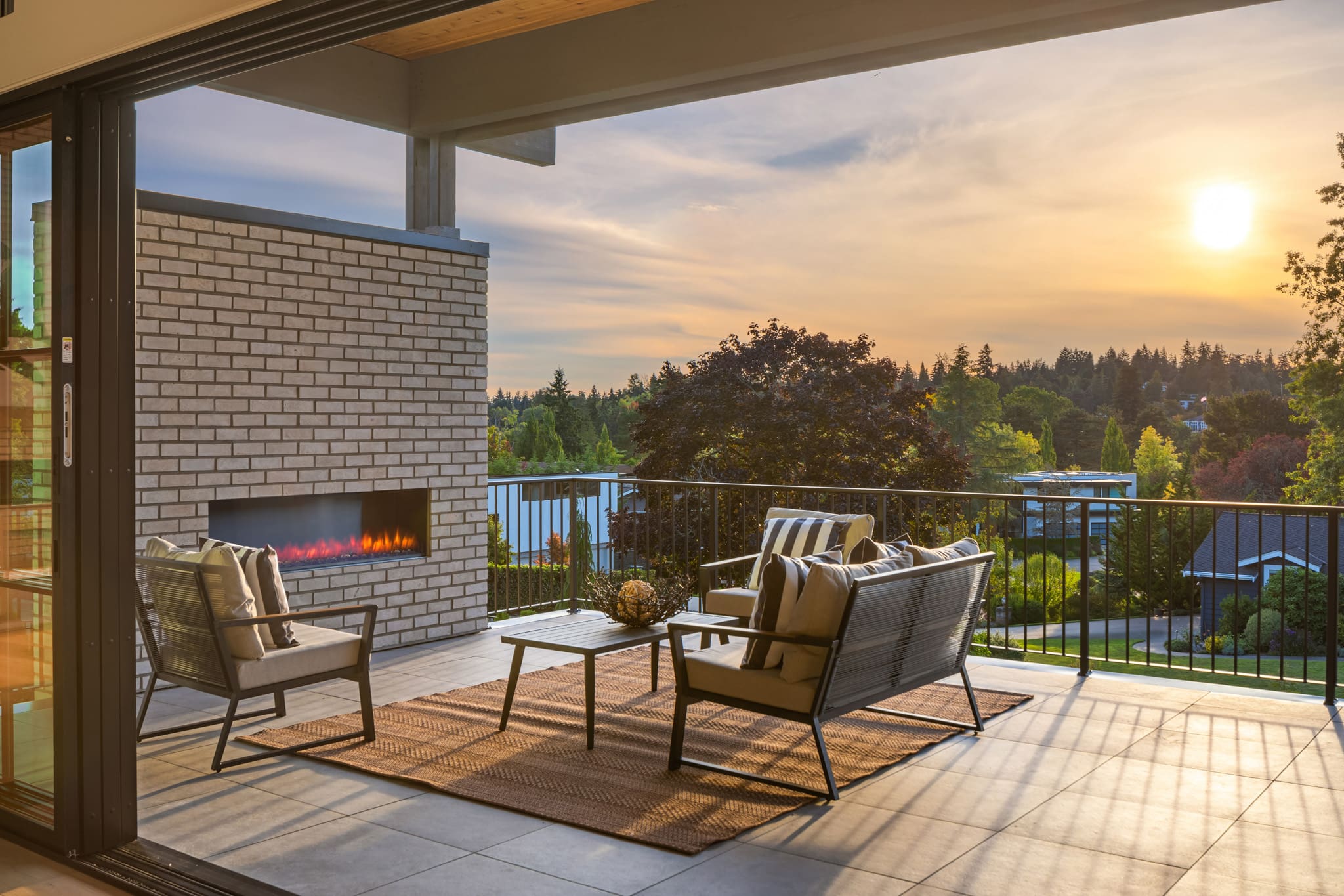 Modern outdoor living space with stylish seating and a cozy fireplace, showcasing a beautiful sunset view in the Pacific Northwest.