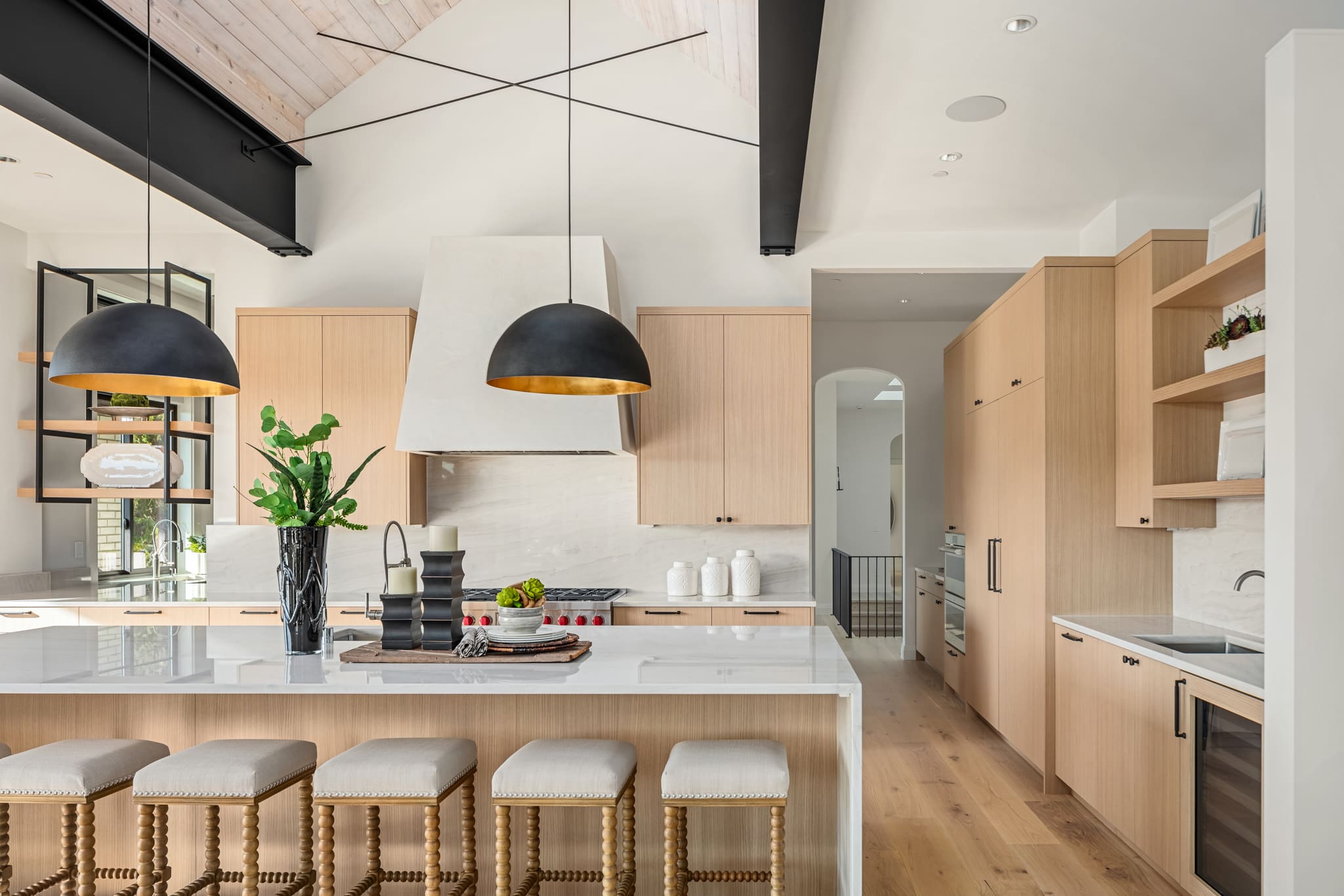 Modern kitchen with natural wood cabinetry, marble countertops, and stylish pendant lighting, located in the Pacific Northwest.