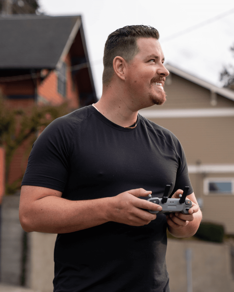 Michael Clark. A man operating a drone in an outdoor residential area, showcasing a modern suburban neighborhood in the Pacific Northwest.
