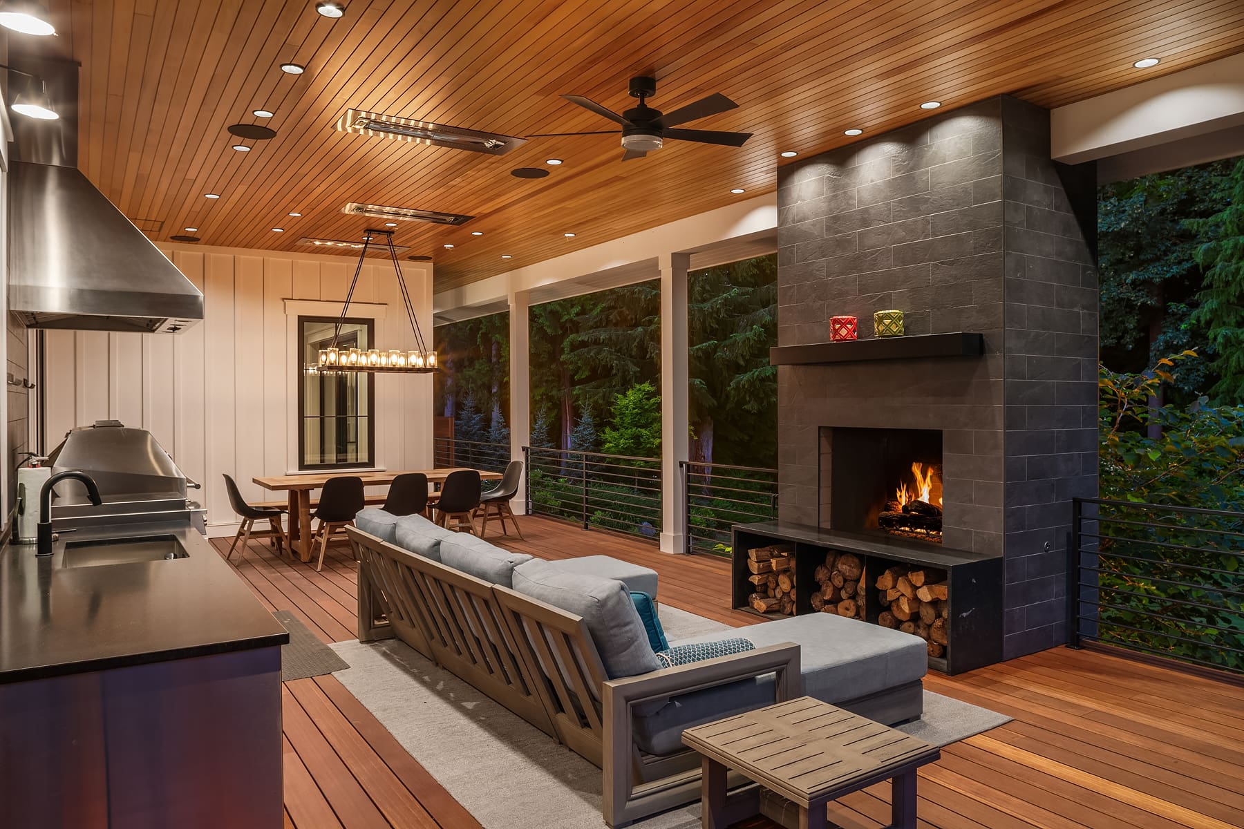 Modern outdoor living space with a cozy fireplace, stylish seating, and dining area, featuring warm wood tones and sleek design elements, located in the Pacific Northwest.