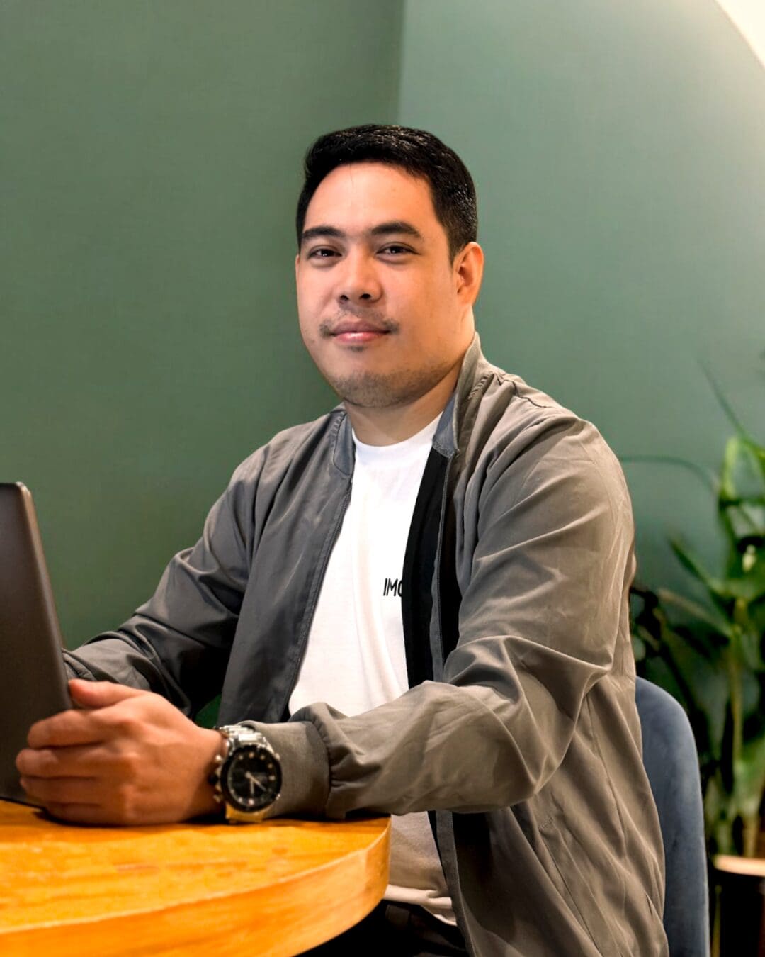 Professional man working on a laptop at a stylish wooden table in a modern office space with green accents, located in the Pacific Northwest.