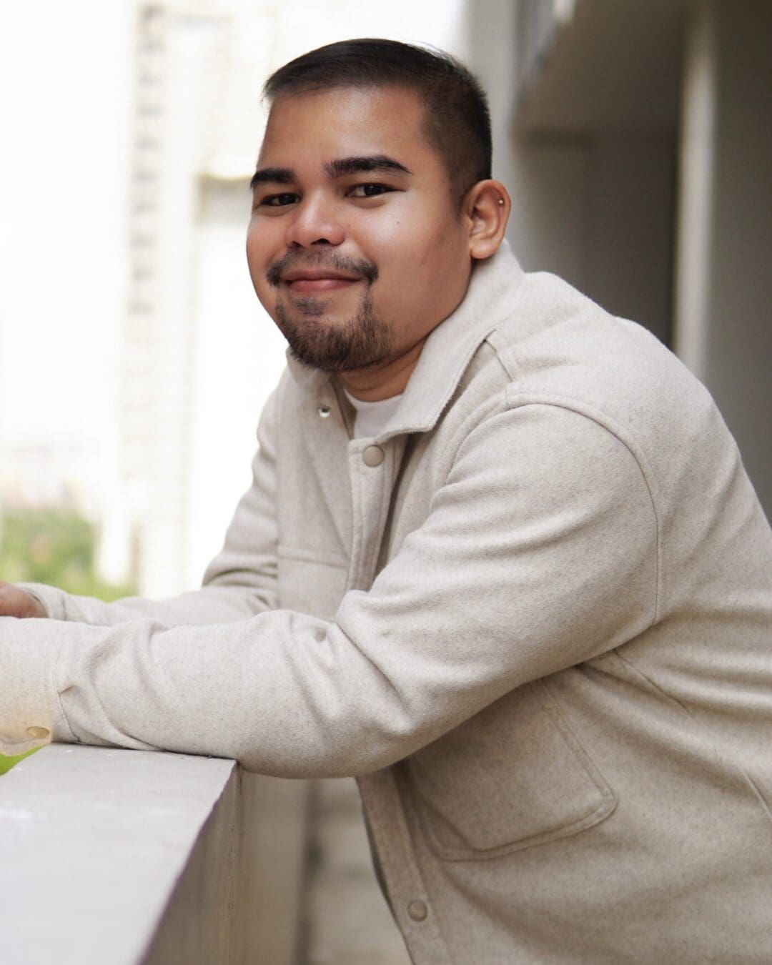 This image features a young man leaning on a balcony railing, showcasing a modern urban setting in a high-rise building. The design conveys a relaxed and contemporary vibe, typical of city living in the Pacific Northwest.