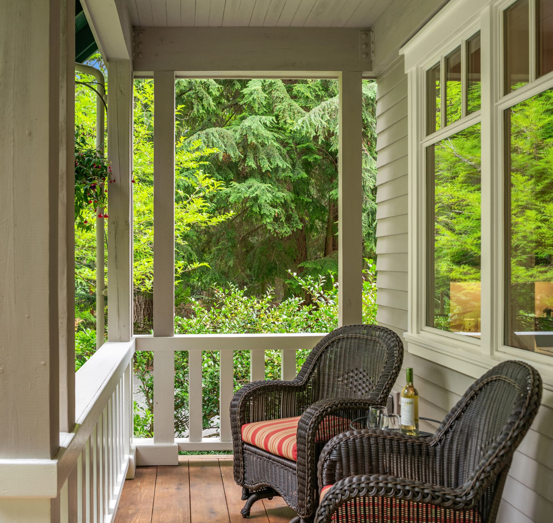 Charming covered porch with cozy wicker chairs and scenic views of lush greenery, located in the Pacific Northwest.