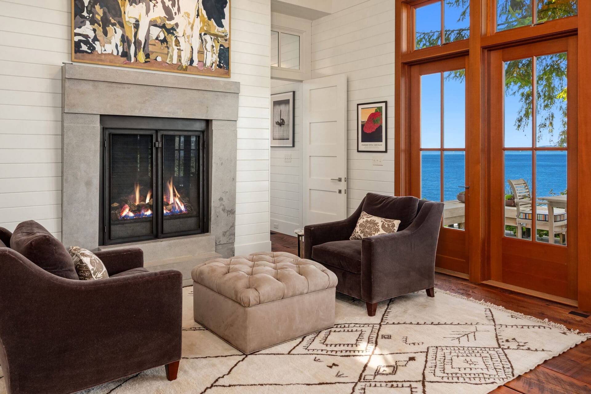 Modern living room with a cozy fireplace, plush seating, and stunning ocean views, located in the Pacific Northwest.