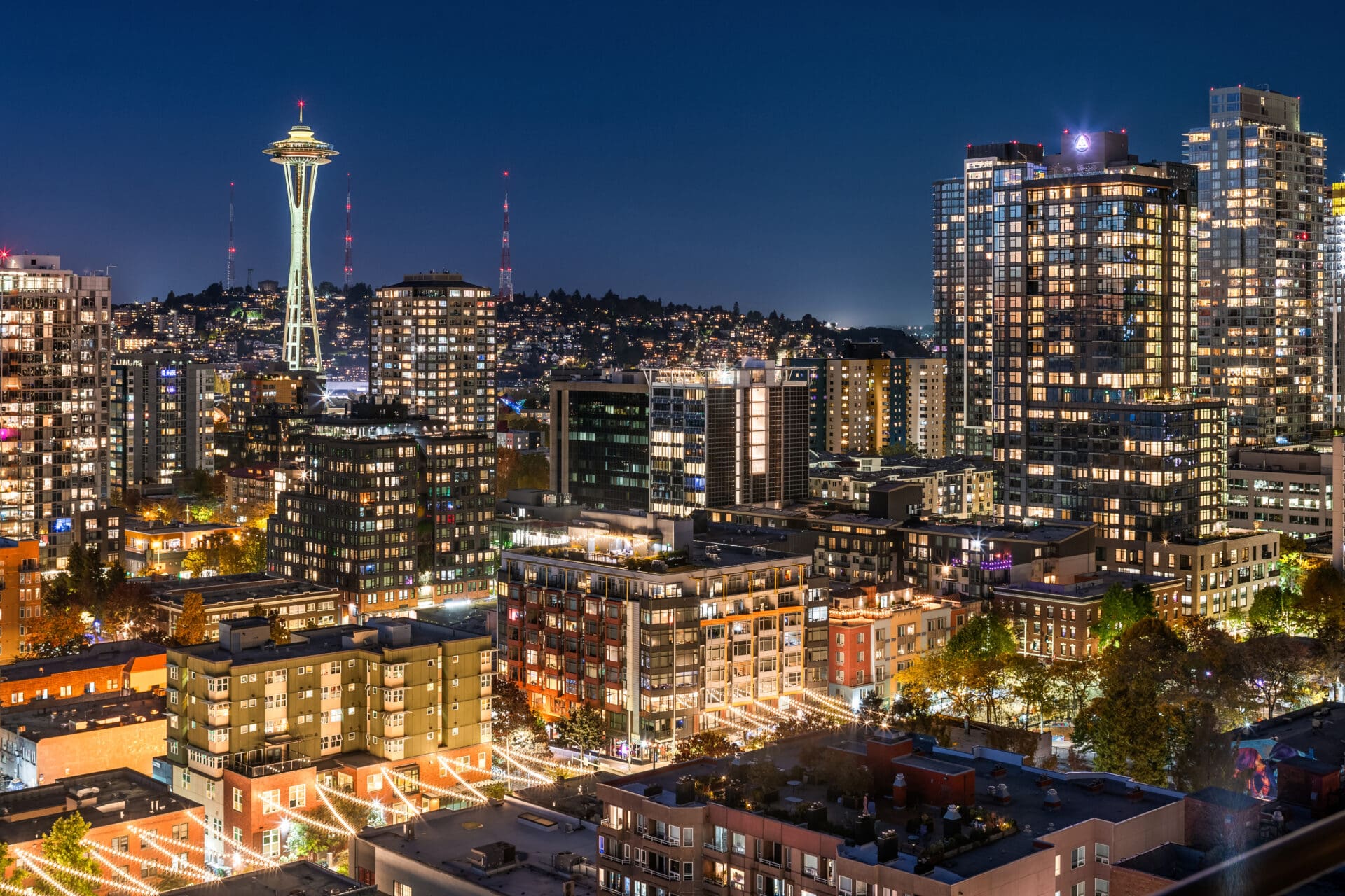 Seattle cityscape at night featuring illuminated skyscrapers and the iconic Space Needle, showcasing a vibrant urban atmosphere in the Pacific Northwest.