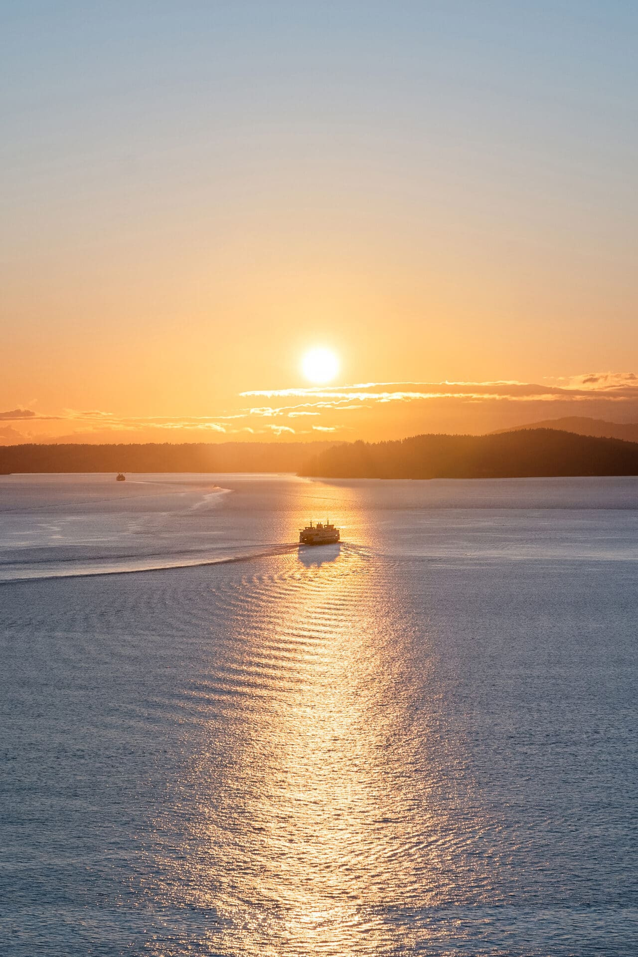 Scenic sunset over water with a ferry navigating through gentle waves, capturing the tranquil beauty of the Pacific Northwest.