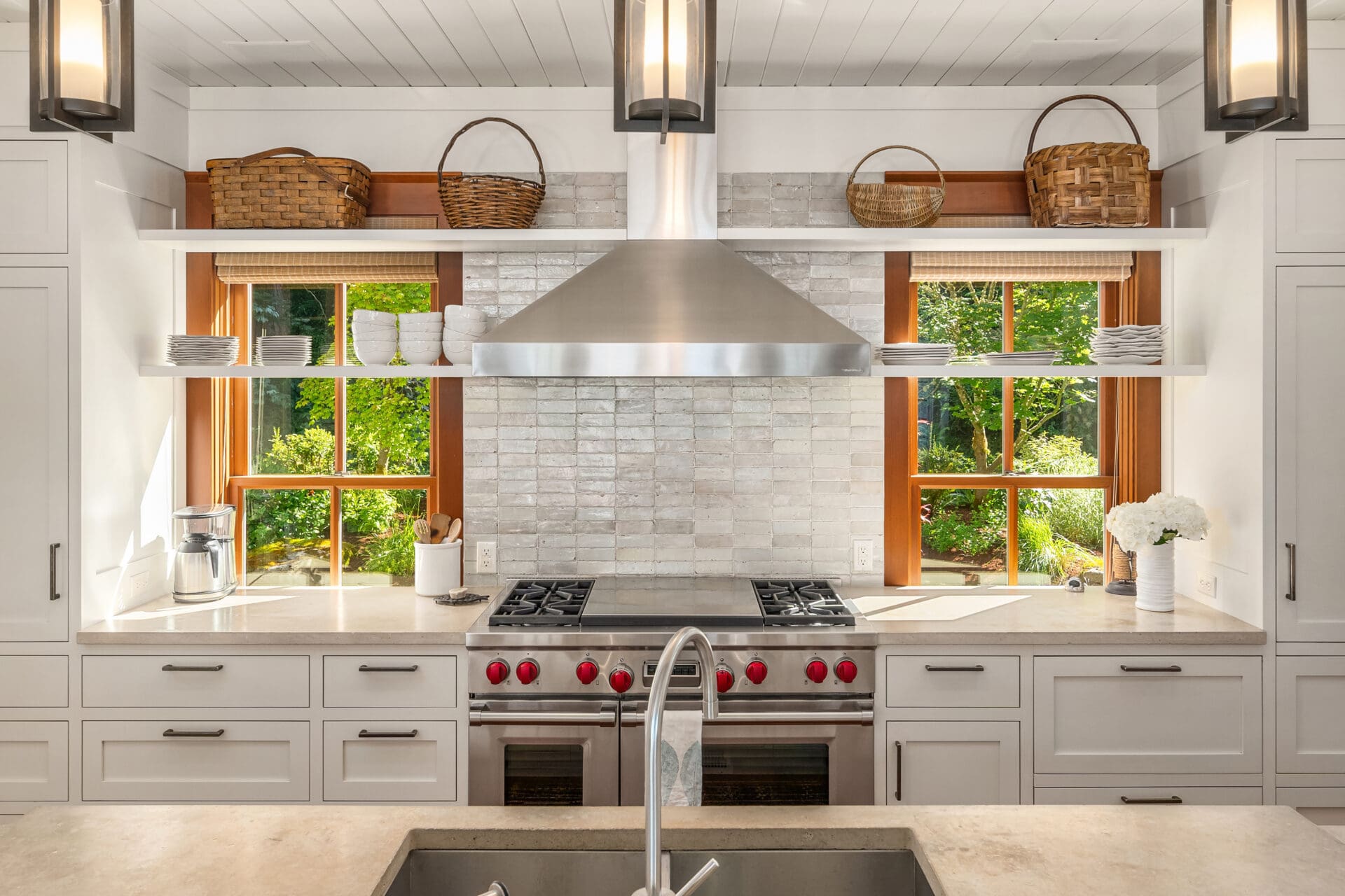 Modern kitchen with stainless steel appliances, white cabinetry, and natural light from large windows in a serene Pacific Northwest setting.