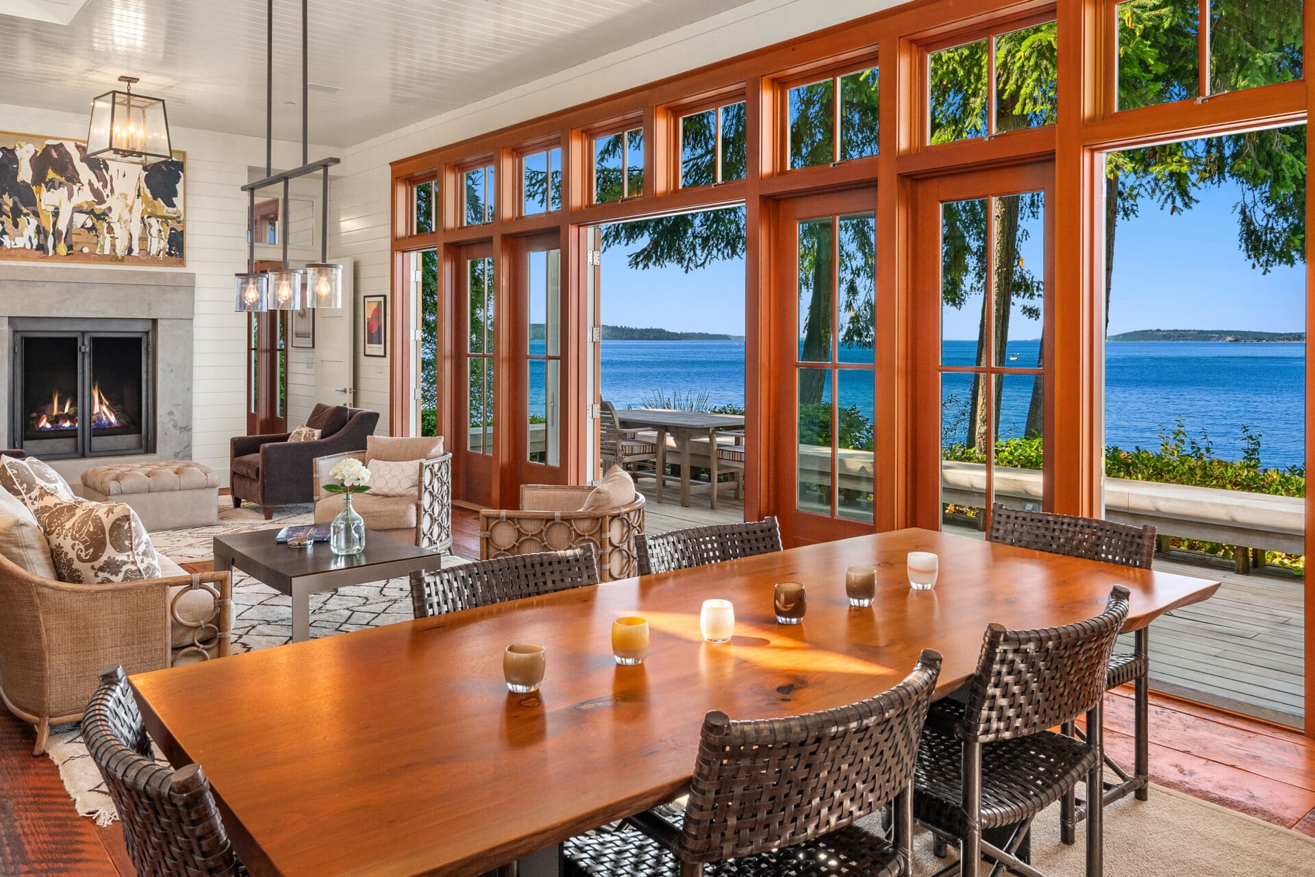 Spacious living area with large windows showcasing stunning waterfront views, featuring a modern design, cozy seating, and a warm color palette, located in the Pacific Northwest.