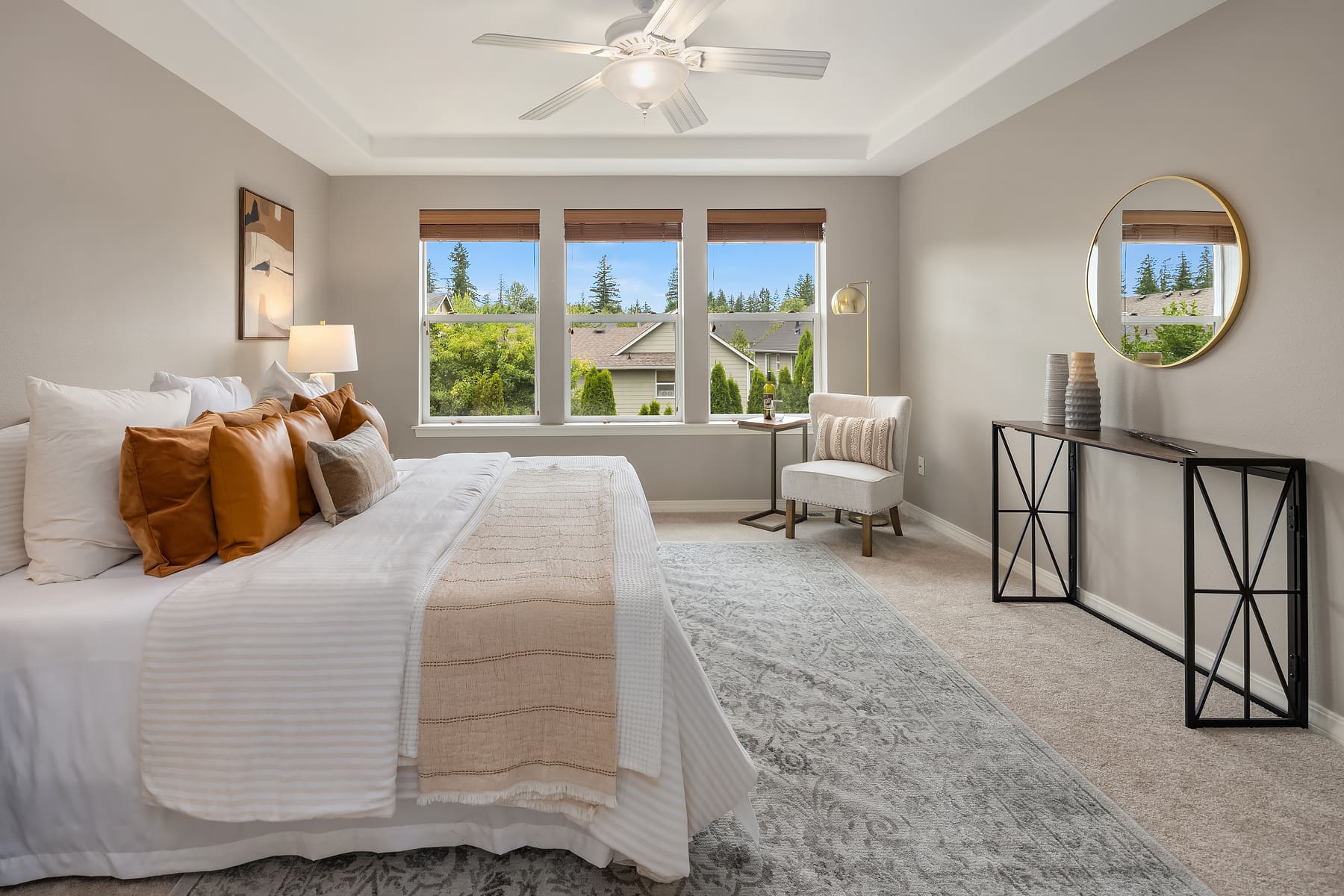 Bright and modern bedroom featuring a cozy bed with decorative pillows, large windows offering lush green views, and stylish furnishings in a Pacific Northwest home.