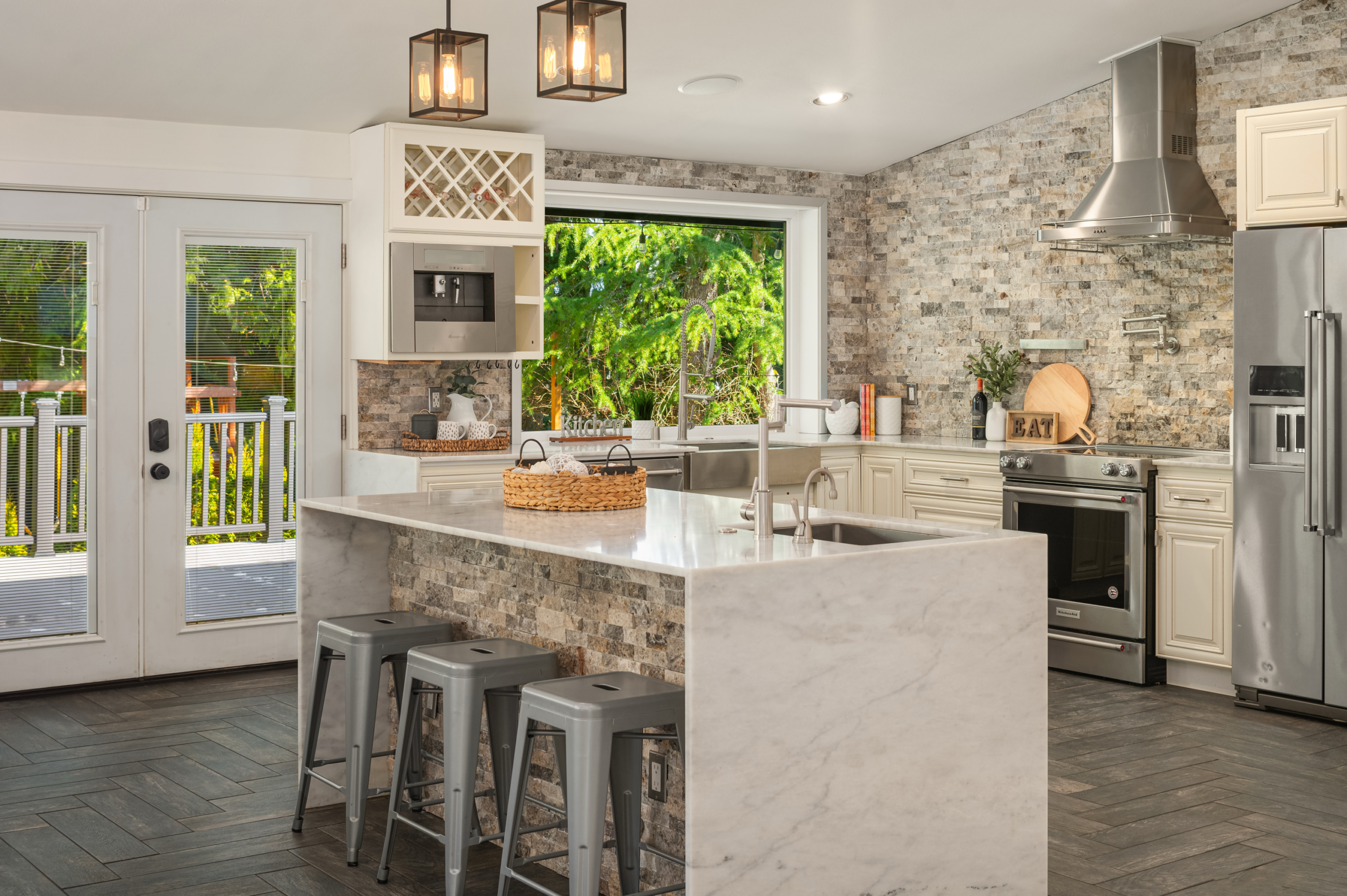 Modern kitchen featuring elegant stone backsplash, stainless steel appliances, and a spacious island with seating. Bright natural light streams through large windows, highlighting the contemporary design in a Pacific Northwest home.