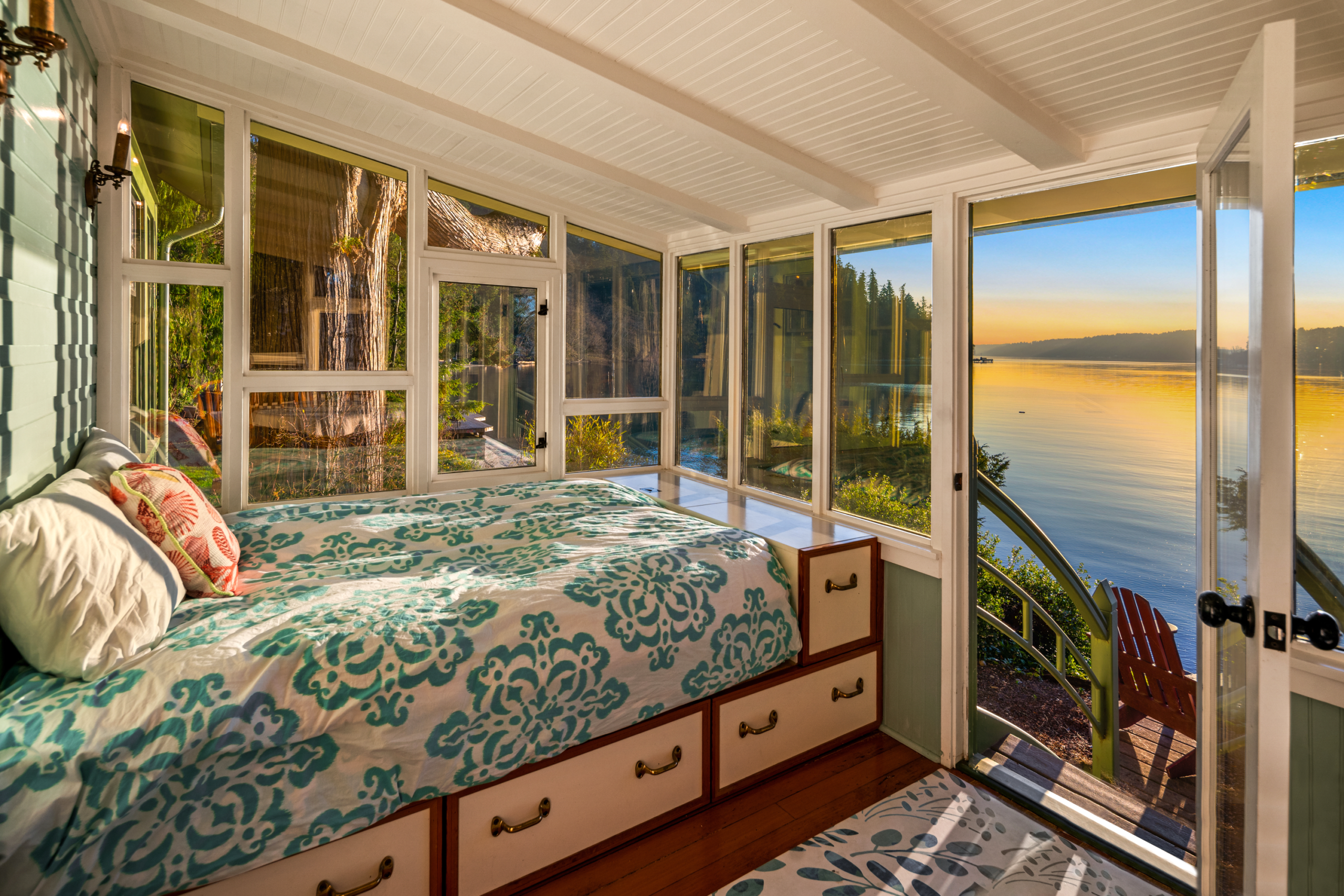 Cozy sunlit bedroom with large windows showcasing stunning lake views, featuring a serene color palette and modern decor, located in the Pacific Northwest.