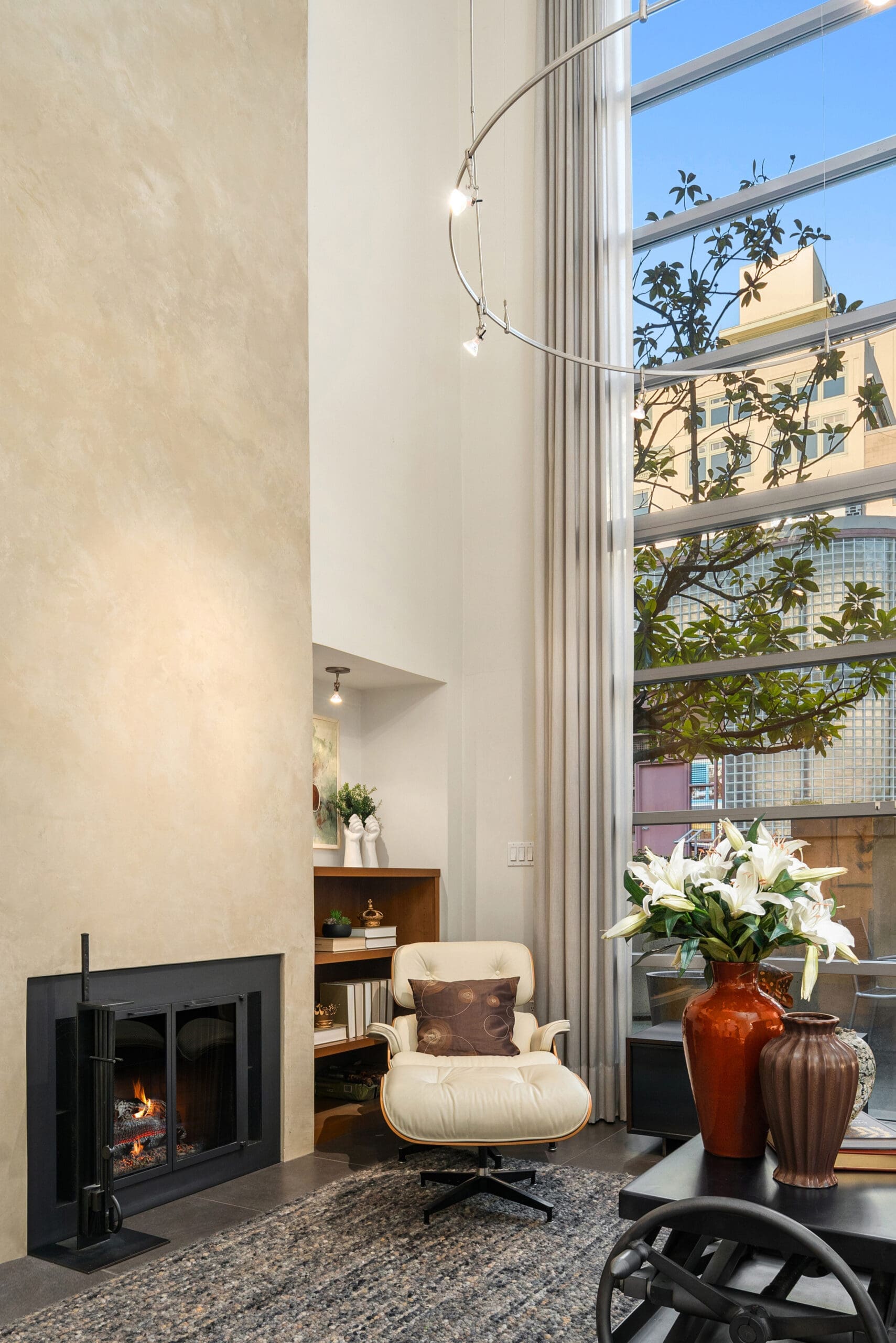 Modern living room with high ceilings, featuring a cozy fireplace, stylish furniture, and large windows offering city views, located in Seattle.