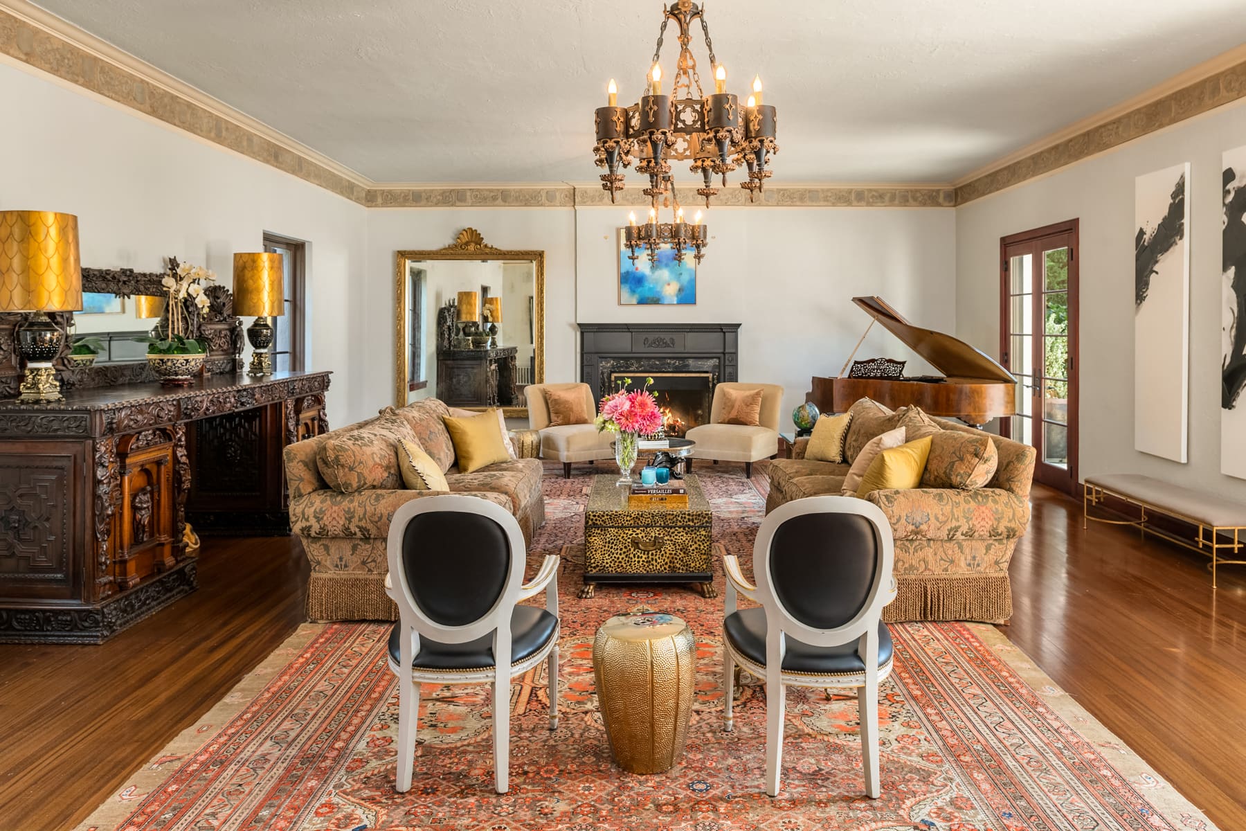 Elegant living room featuring vintage furnishings, a grand chandelier, and a classic piano, set in a beautifully decorated space with rich wood accents, located in the Pacific Northwest.