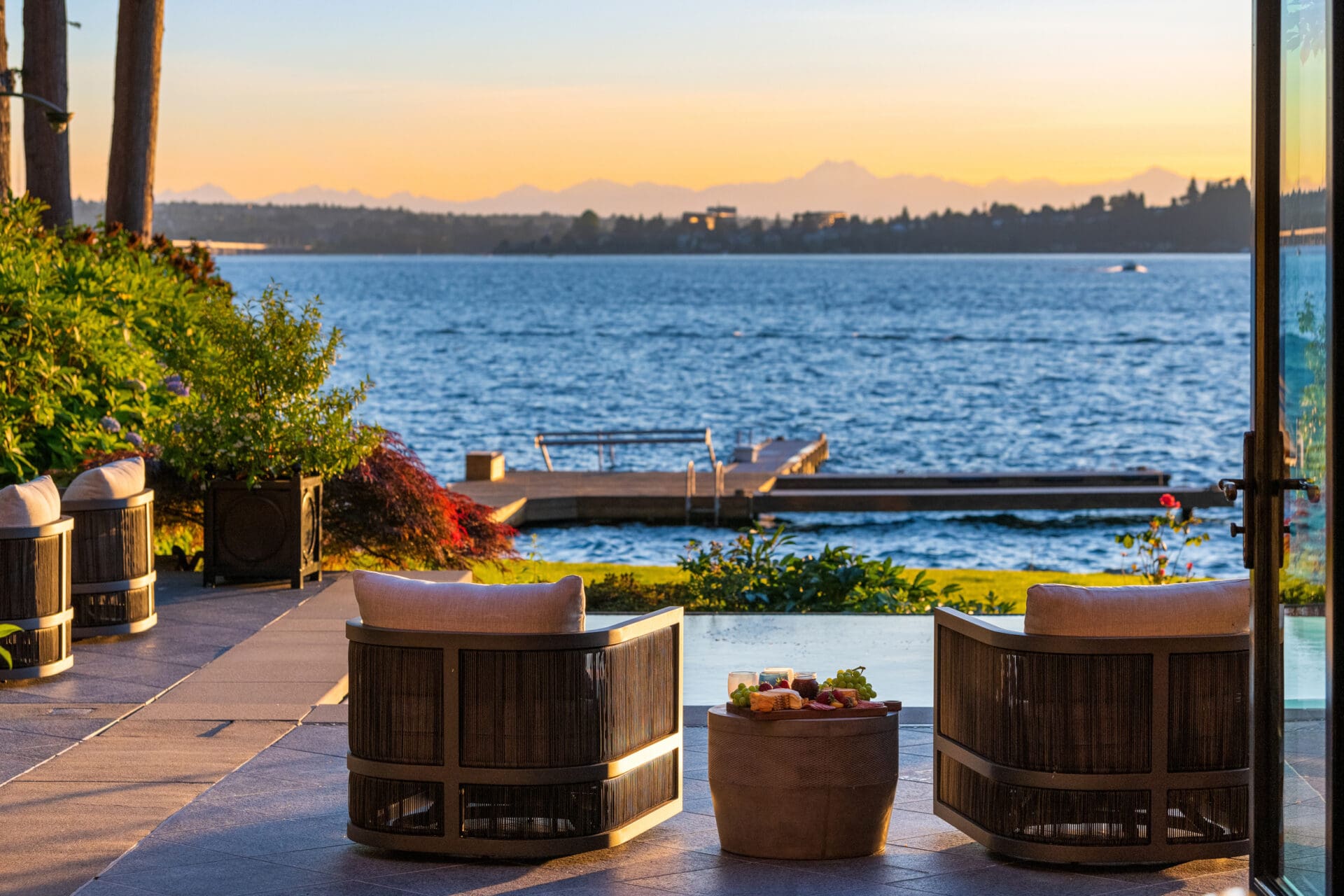 Luxurious outdoor living space with modern seating and a stunning view of the water at sunset, located in the Pacific Northwest.