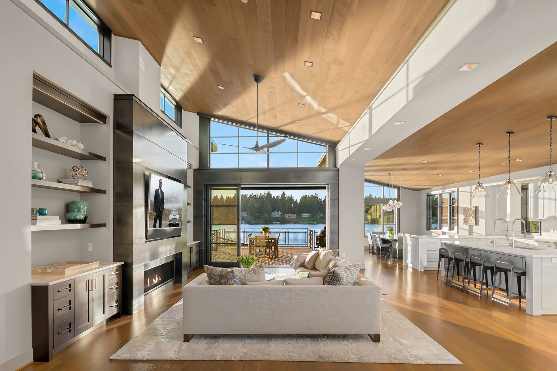 Modern waterfront living room with large windows, showcasing stunning lake views and abundant natural light, featuring elegant wood accents and contemporary furnishings in the Pacific Northwest.