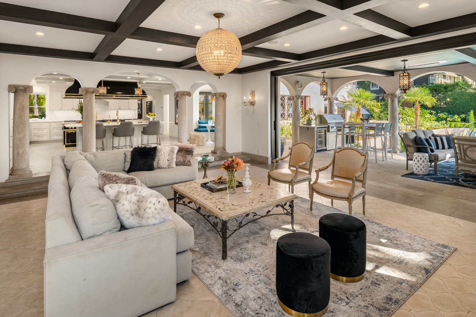 Spacious modern living room with elegant furnishings and an open layout, featuring a stylish chandelier, plush seating, and views of a lush outdoor patio, located in the Pacific Northwest.