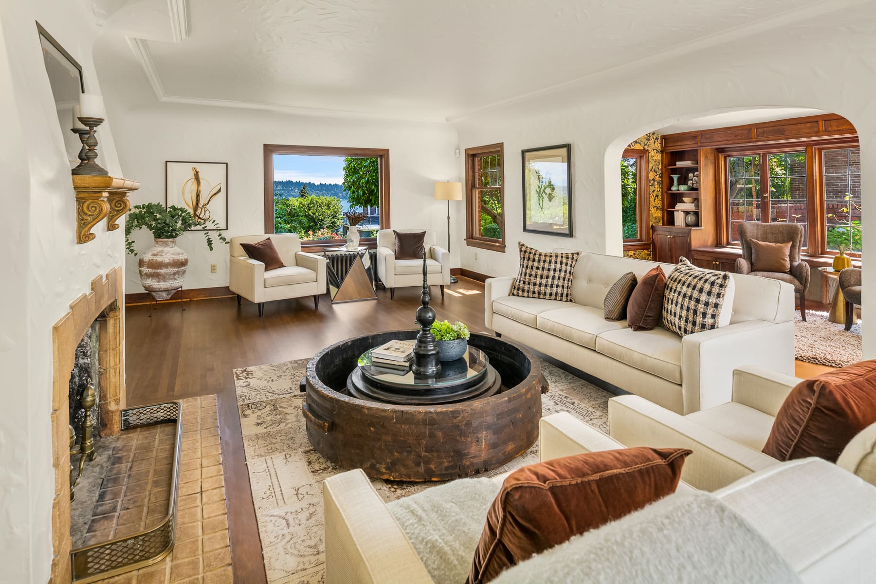 Bright and inviting living room featuring elegant furnishings, a unique round coffee table, and large windows showcasing lush outdoor views. Located in the Pacific Northwest, this space blends modern comfort with classic design elements.