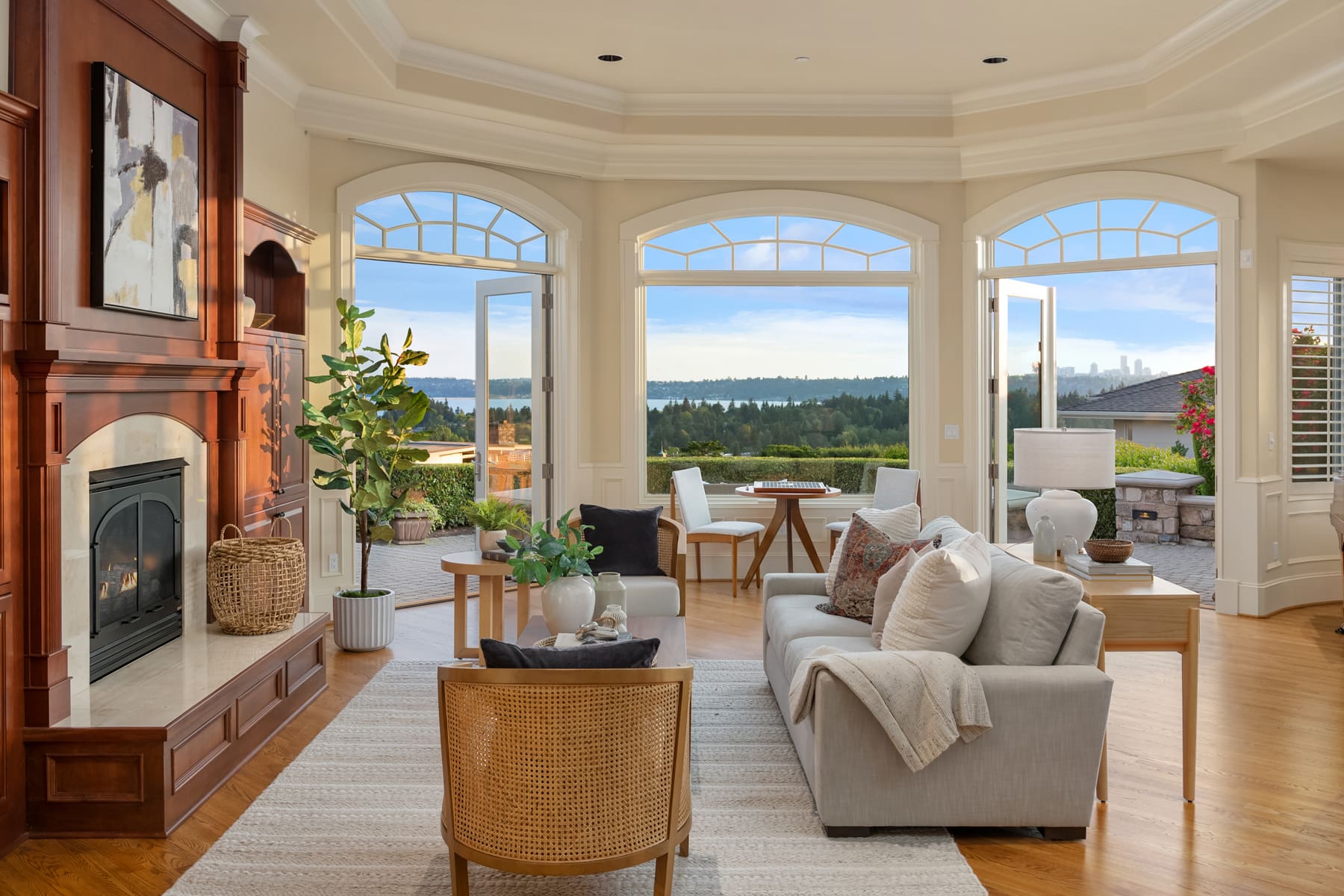 Spacious living room with modern design features, showcasing a cozy fireplace and large windows offering stunning views of the Seattle skyline and surrounding greenery, perfect for relaxation in the Pacific Northwest.