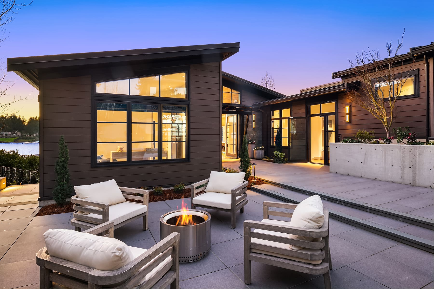 Modern outdoor living space with a fire pit and comfortable seating, showcasing sleek design and warm lighting, located in the Pacific Northwest.