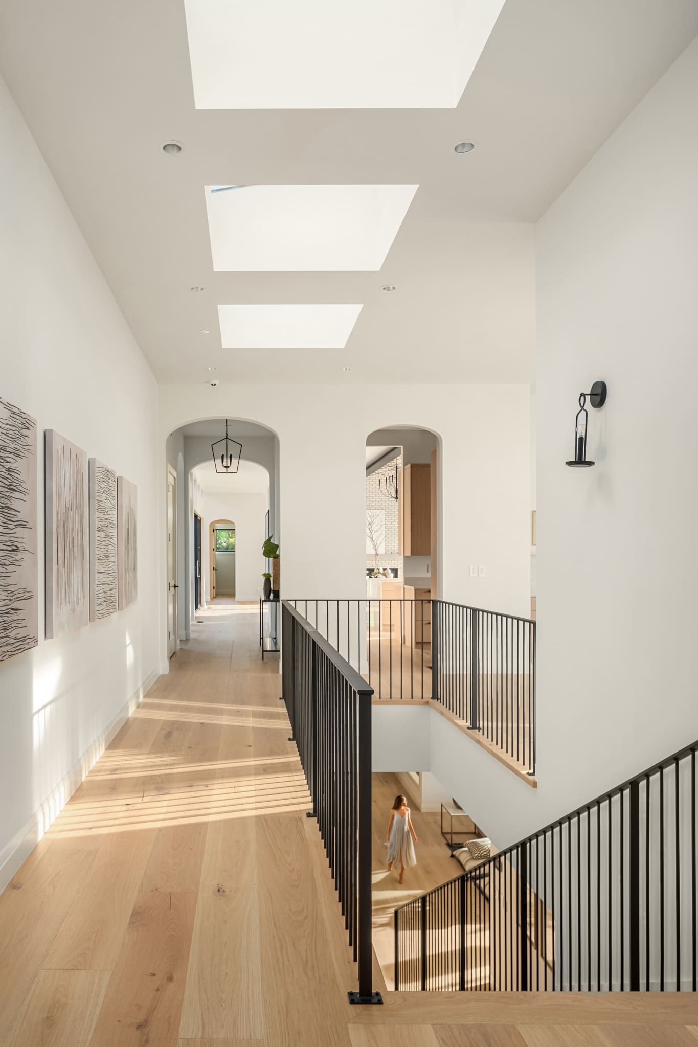Bright and airy modern hallway featuring skylights and elegant black railings, showcasing contemporary design elements in a Pacific Northwest home.