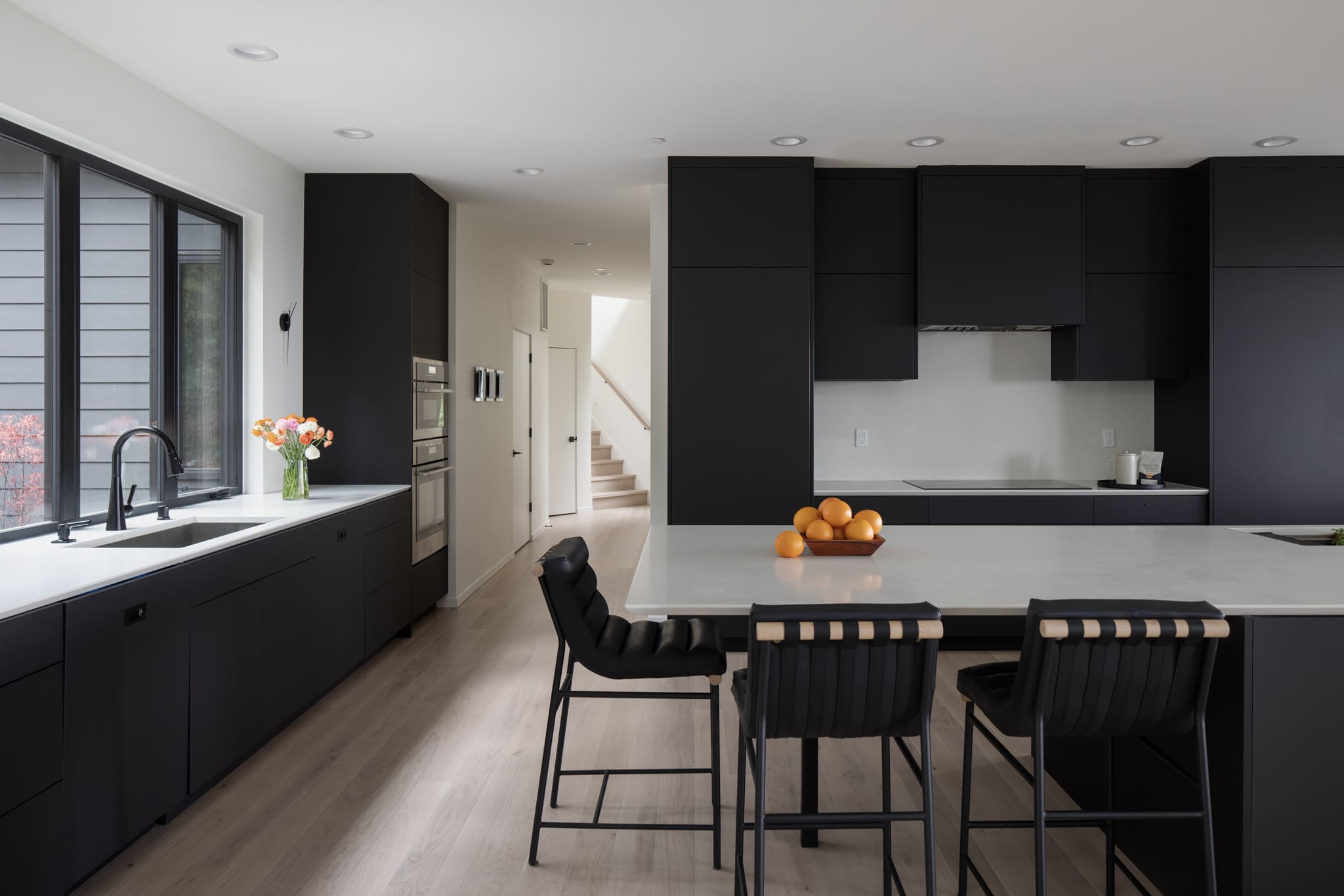 Modern kitchen featuring sleek black cabinetry, a large island with a light countertop, and stylish bar stools, located in the Pacific Northwest.