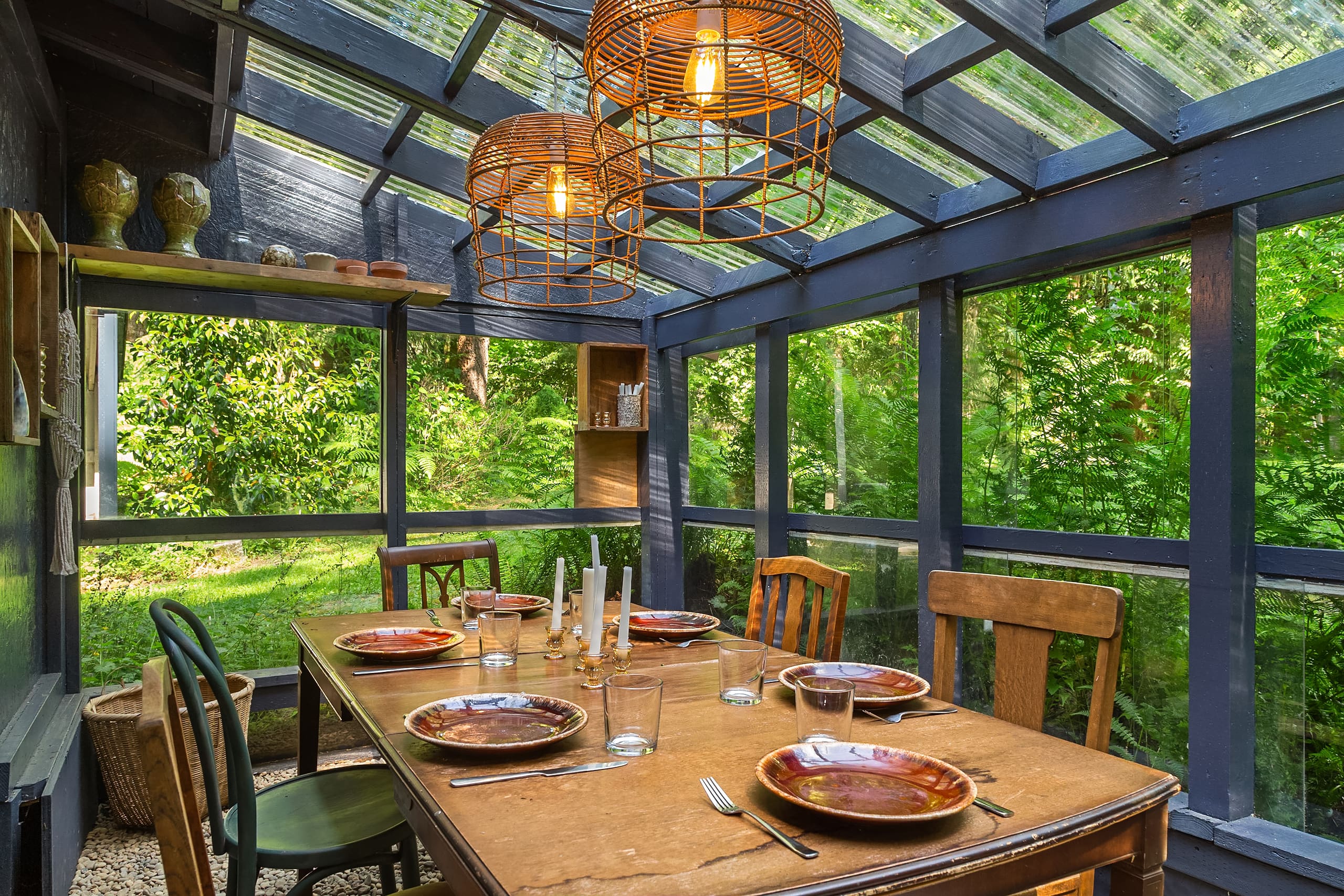 Bright and inviting dining space featuring a rustic wooden table set for a meal, surrounded by greenery and natural light filtering through a glass-roofed structure in the Pacific Northwest.