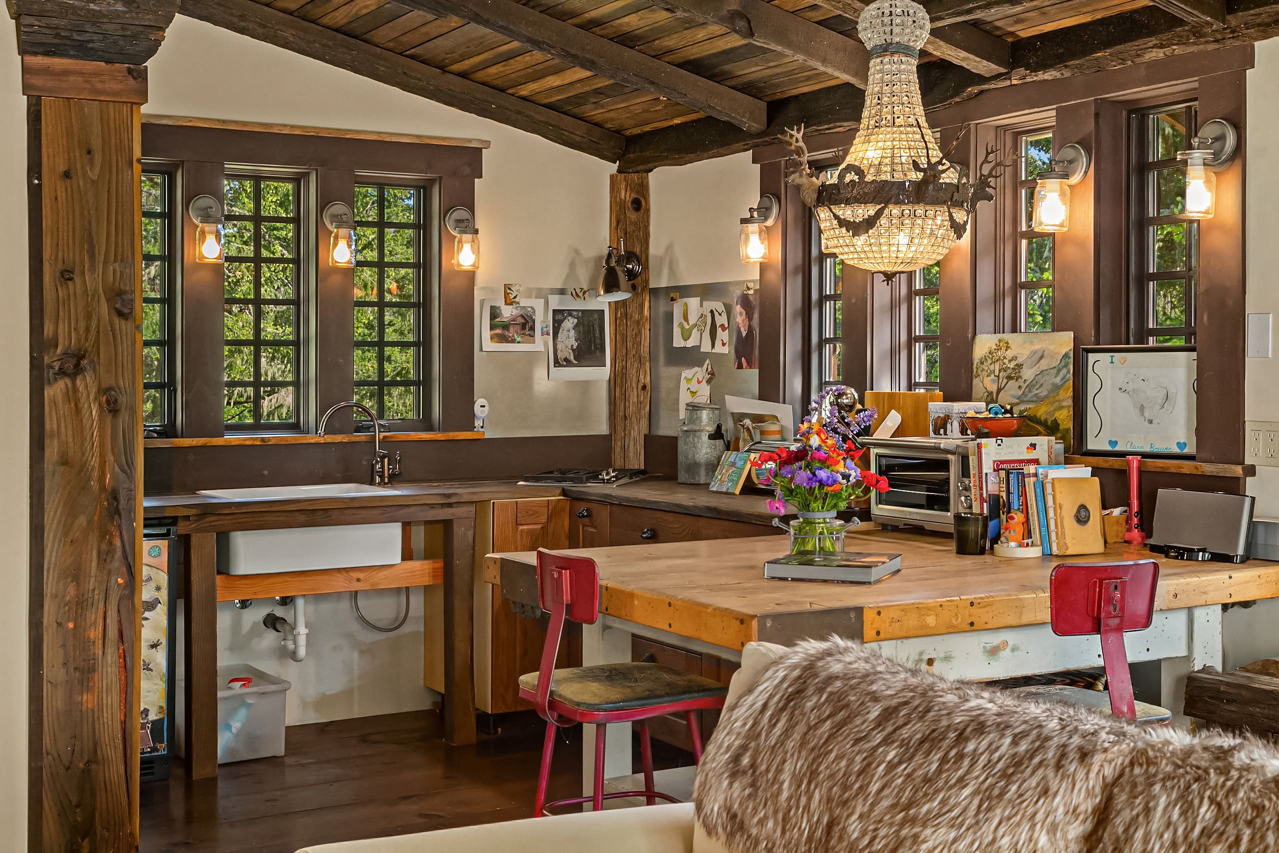 Cozy kitchen space featuring rustic wood beams, a charming chandelier, and a farmhouse sink, designed with a blend of modern and vintage elements. Located in the Pacific Northwest.