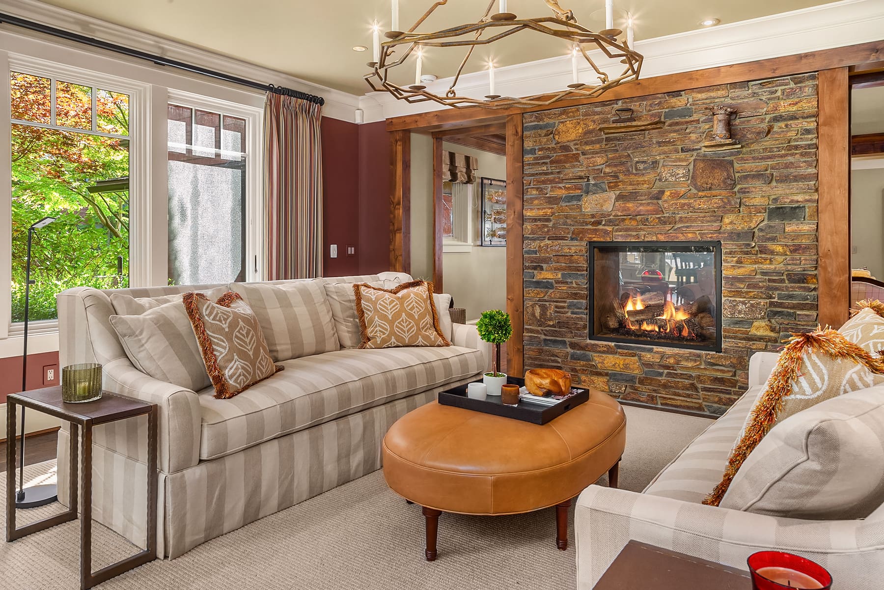Cozy living room featuring a modern design with a stone fireplace, plush sofas, and a stylish leather ottoman, located in the Pacific Northwest.