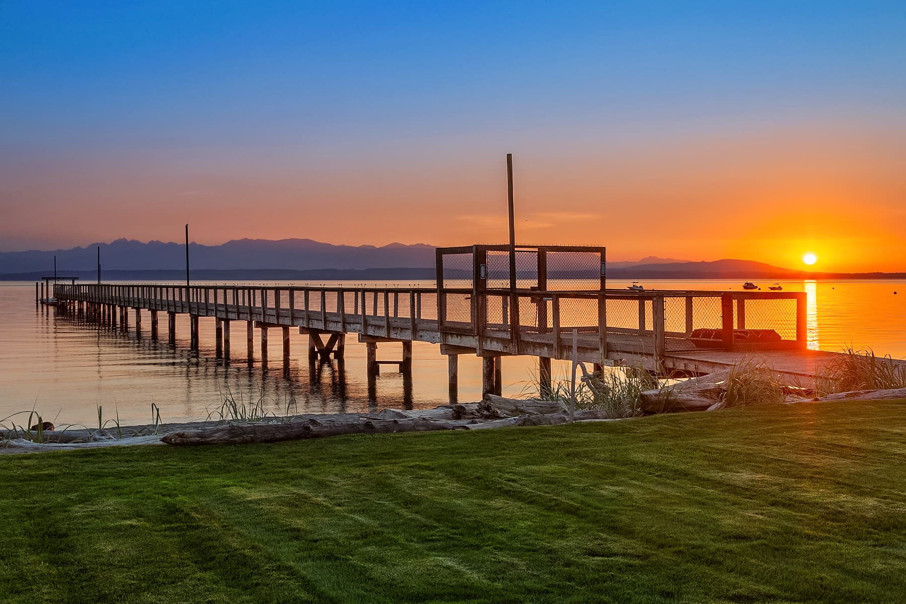 Scenic waterfront pier at sunset, showcasing serene reflections on water with vibrant orange and blue hues, located in the Pacific Northwest.