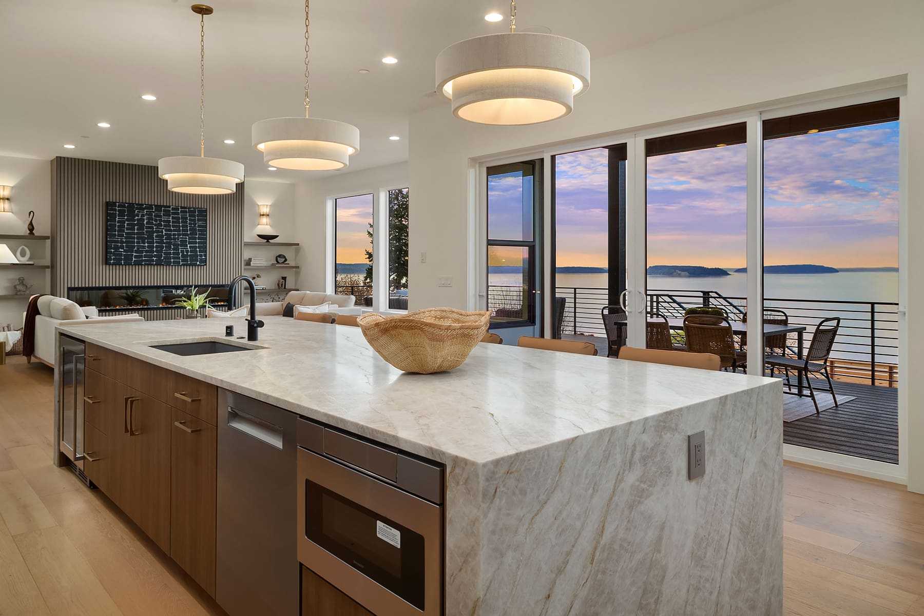 Modern kitchen with elegant marble island and stylish lighting, featuring large windows that offer stunning waterfront views in the Pacific Northwest.