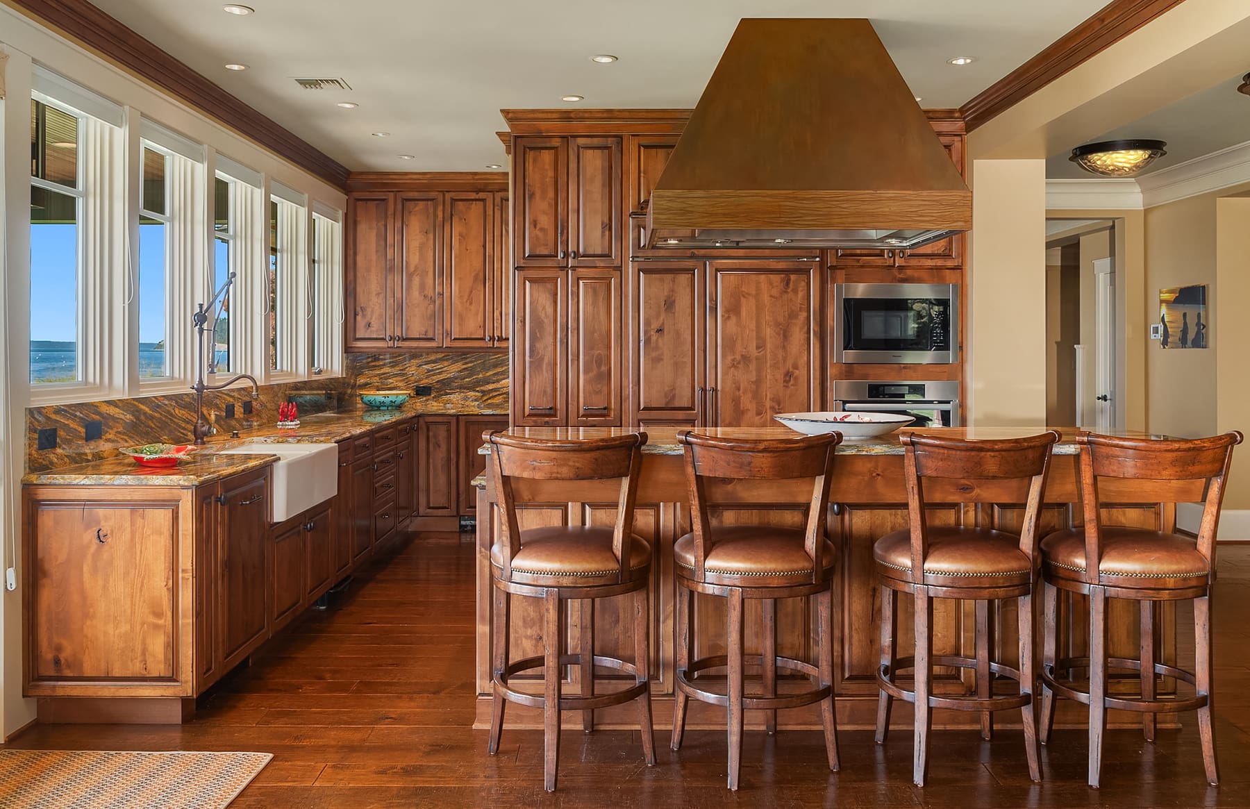 Elegant kitchen with rich wooden cabinetry, granite countertops, and modern appliances, featuring a spacious island with bar seating, located in the Pacific Northwest.