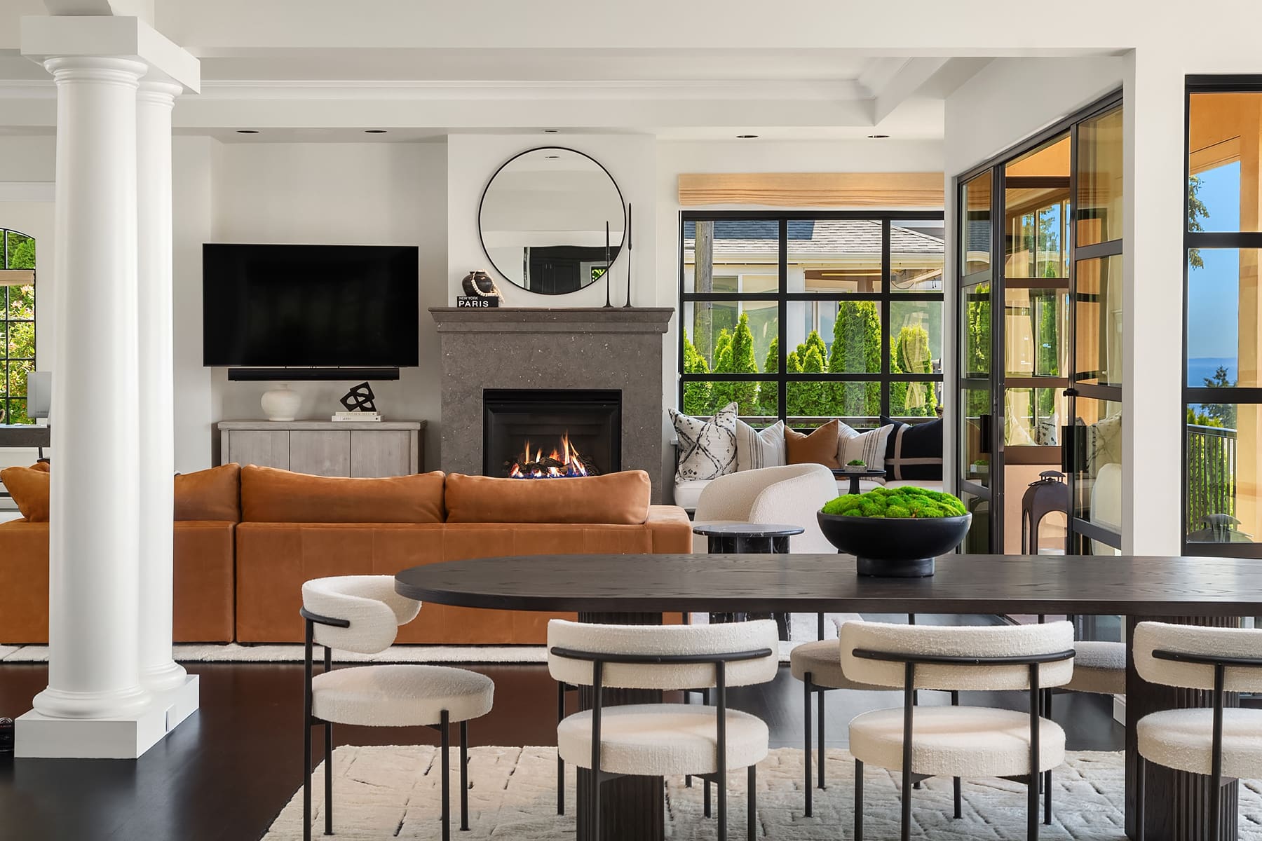 Modern living room with a cozy fireplace, stylish furniture, and large windows showcasing greenery, located in the Pacific Northwest.
