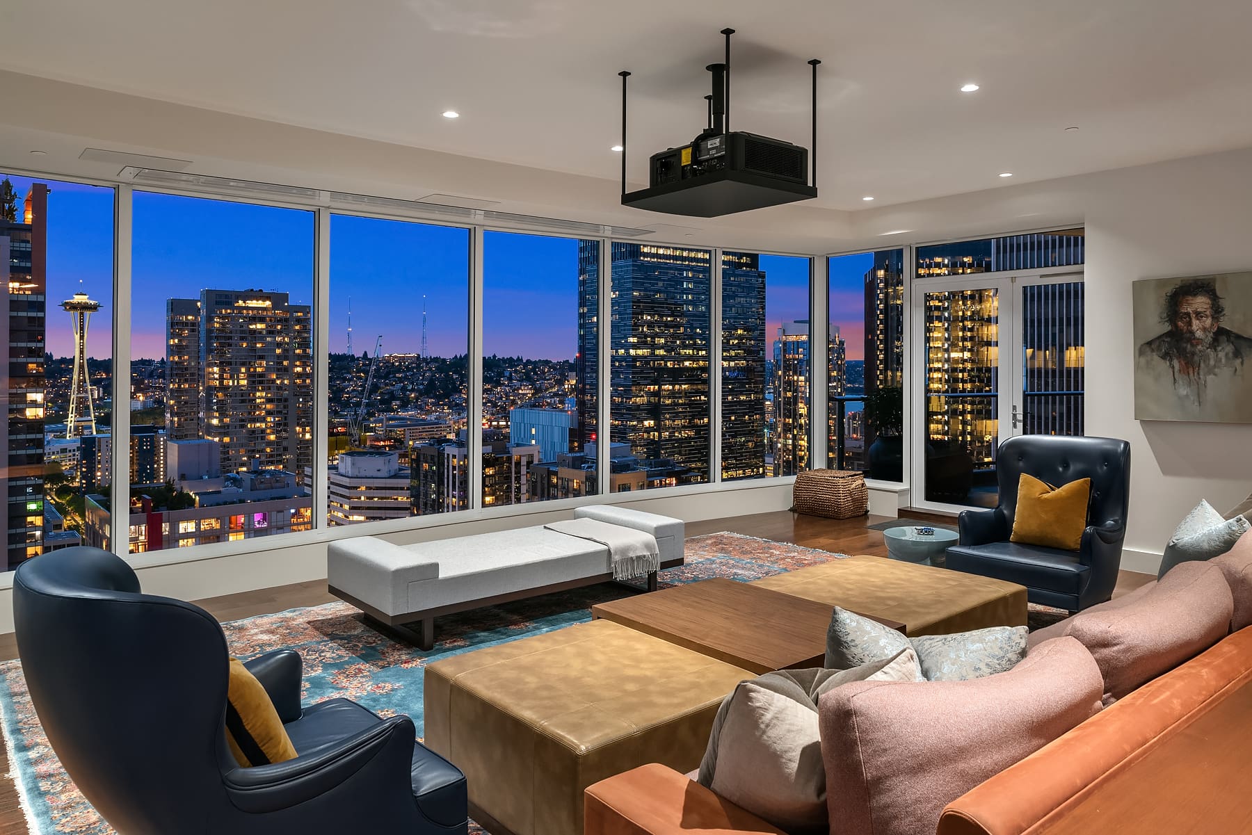 Modern living room with panoramic city views at twilight, featuring stylish seating, a projector, and elegant decor, located in Seattle.
